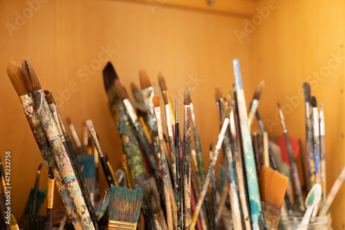 Many paintbrushes in pots for art and artist in a bookcase