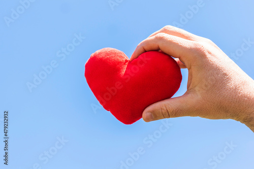 Red heart on man hand with sky background  valentines day concept