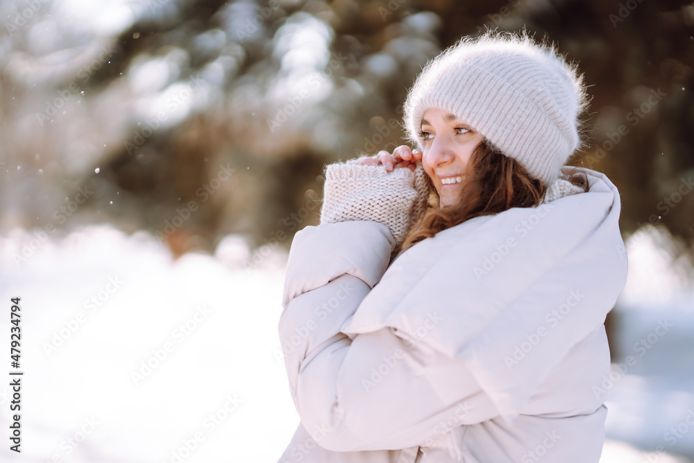 Obraz premium Young woman in winter style clothes walking in the snowy park. Winter fashion, holidays, nature, travel concept.
