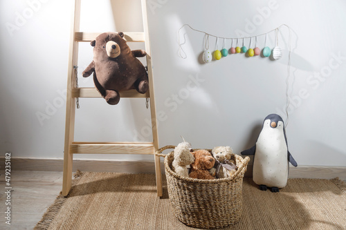 Fragment of the interior of the children's room, decorated for Easter. A ladder with a bear, a garland of fake colored eggs. Easter card photo