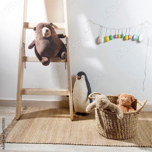 Fragment of the interior of the children's room, decorated for Easter. A ladder with a bear, a garland of fake colored eggs. Easter card photo