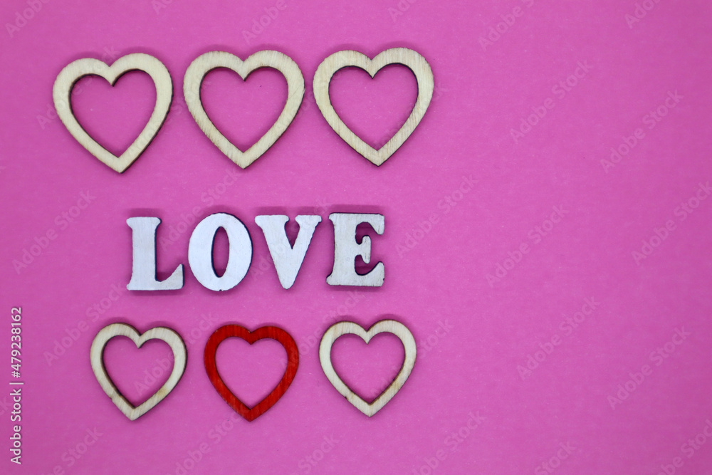 Valentine's Day concept. Wooden letters Love and small hearts on a pink background. Top view. Flat lay.
