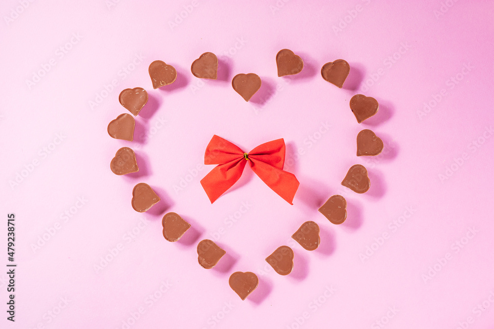 A heart shape made from chocolate pralines  for Valentine day or International woman's day or any celebration of love. Purple background, nice and simple concept. Top view.
