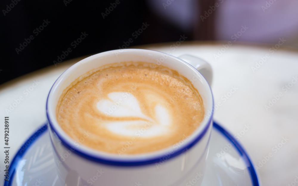 One Cup of cappuccino with latte art. Coffee in blue cup on wooden table in cafe. Concept of easy breakfast. One Cup of cappuccino with latte art. Coffee in blue cup on wooden table in cafe. Concept of easy breakfast.
