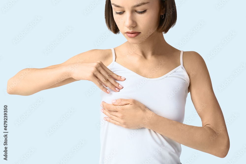 Young woman feeling discomfort in her breast on light background. Cancer awareness concept Young woman feeling discomfort in her breast on light background. Cancer awareness concept
