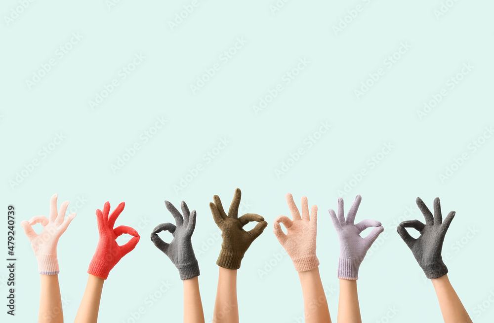 Women in warm gloves showing OK gesture on blue background