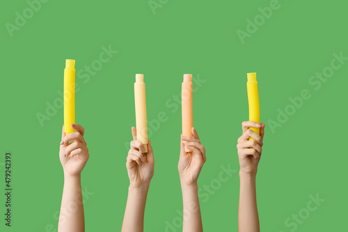 Hands with popular pop tubes on color background