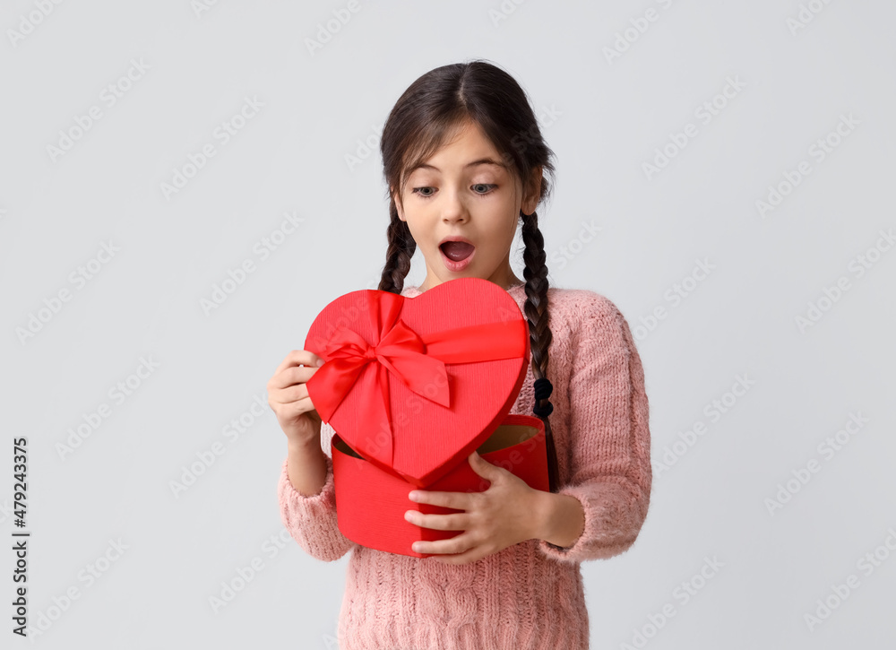 Surprised little girl with gift on grey background. Valentine's Day celebration Surprised little girl with gift on grey background. Valentine's Day celebration