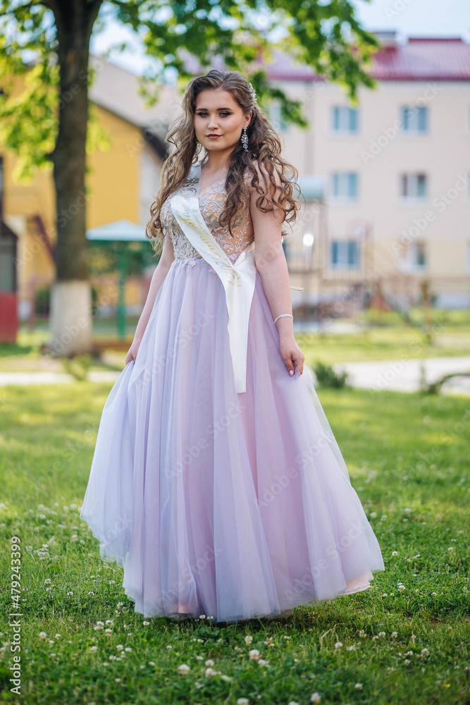 Beautiful schoolgirl in dress at the prom at school.