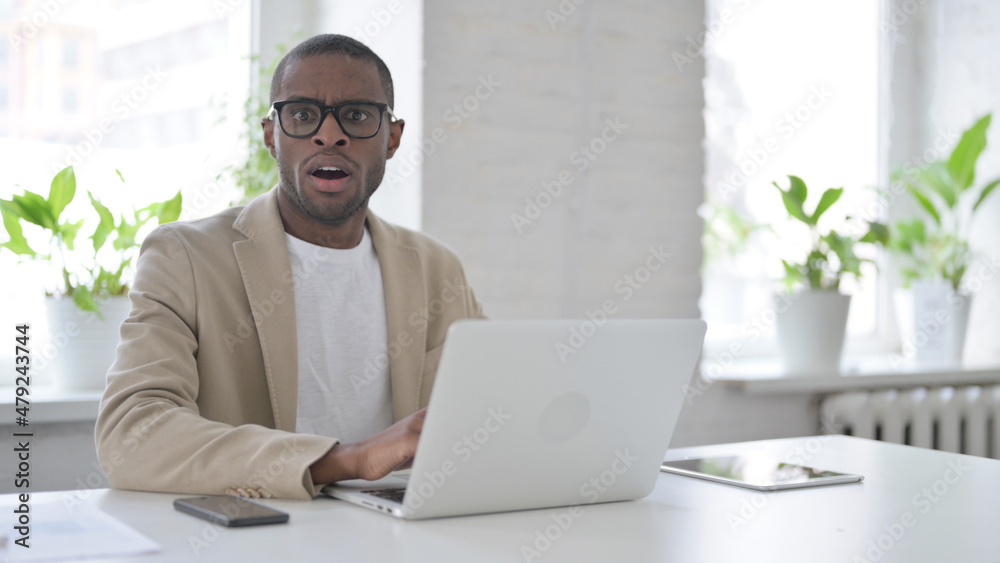 African Man Feeling Shocked while using Laptop in Office African Man Feeling Shocked while using Laptop in Office
