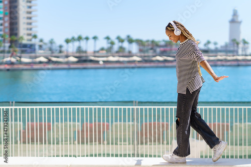 Young black girl balancing while strolling along the harbor of a coastal city. photo