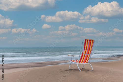 Fototapeta Naklejka Na Ścianę i Meble -  Empty striped beach chair on top of a dune facing the sea. Horizontal photo