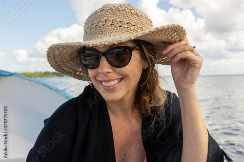 Pretty woman wearing large floppy hat and sunglasses enjoying vacation on a boat on the tropical island of Cozumel, Mexico photo