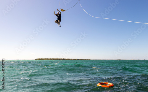 Man falls from spinnaker ride high in the air into the deep blue ocean water near Cozumel, Mexico for an adventure. photo