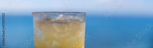 Ice cold margarita with tequila, lime juice and a salted rim in a glass with an ocean front view. A refreshing drink with alcohol during a tropical island vacation.  photo