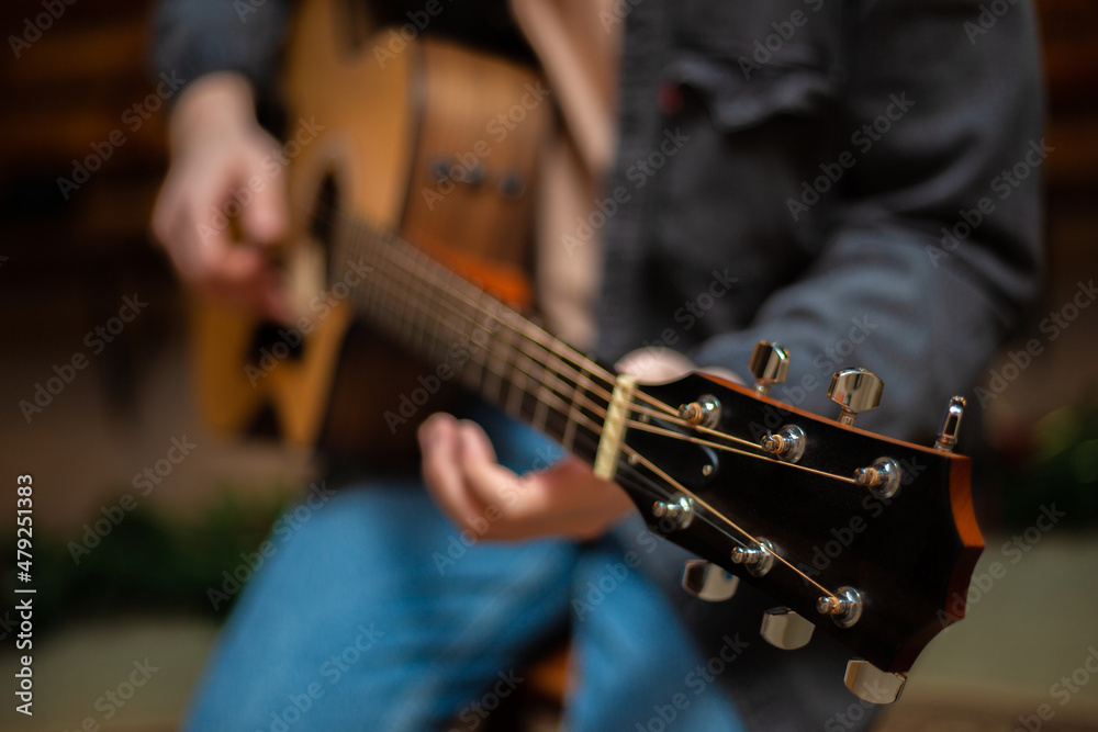 Fototapeta premium A guy clamps a chord on an acoustic guitar with close-up