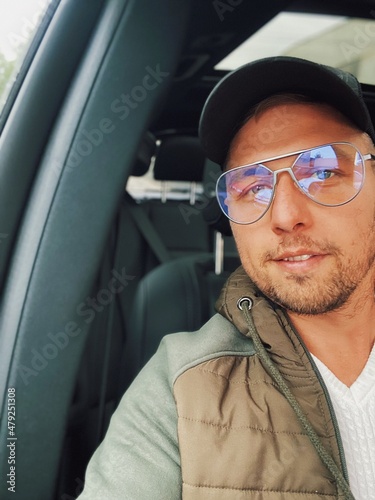 Man in a car wearing a cap and aviator glasses