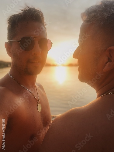 Two Men Enjoying a Serene Sunset by the Water, Capturing a Peaceful, Intimate Moment