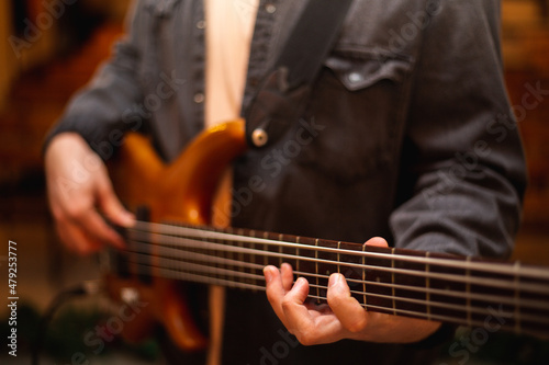 A young guy with a beard plays a bass guitar with five strings