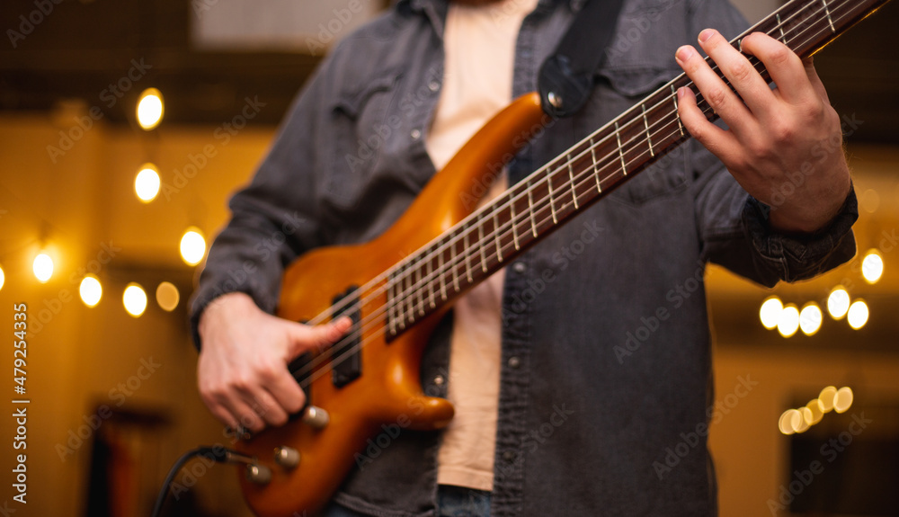 A young guy with a beard plays a bass guitar with five strings