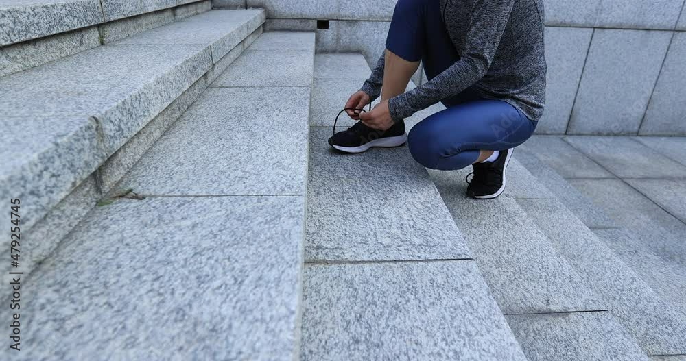 Fitness sports woman tying shoelace and running up stairs in city Fitness sports woman tying shoelace and running up stairs in city