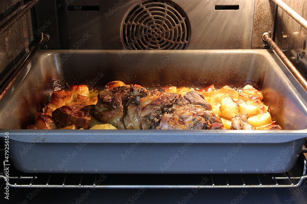 Roasting lamb meat and potatoes in a pan in an oven. Shallow depth of field, selective focus Roasting lamb meat and potatoes in a pan in an oven. Shallow depth of field, selective focus