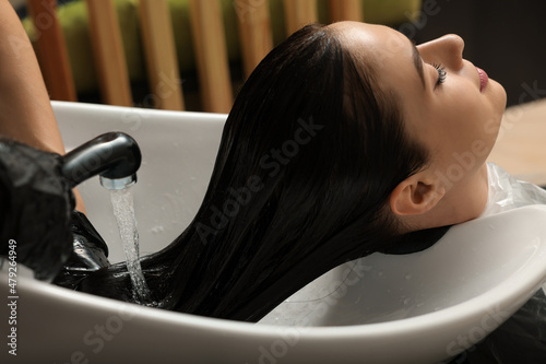 Принти на полотні Hairdresser rinsing out dye from woman's hair in beauty salon