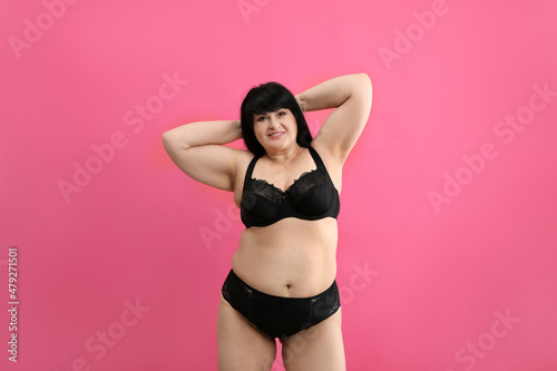 Fototapeta Naklejka Na Ścianę i Meble -  Beautiful overweight woman in black underwear on pink background. Plus-size model