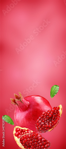 Pomegranate with slice and leafs flying on pomegranate colour background. Background for label, package design. Vertical view