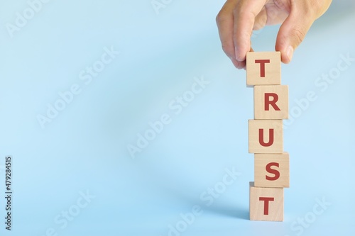Build trust concept. Hand stacking wooden blocks with word trust. photo