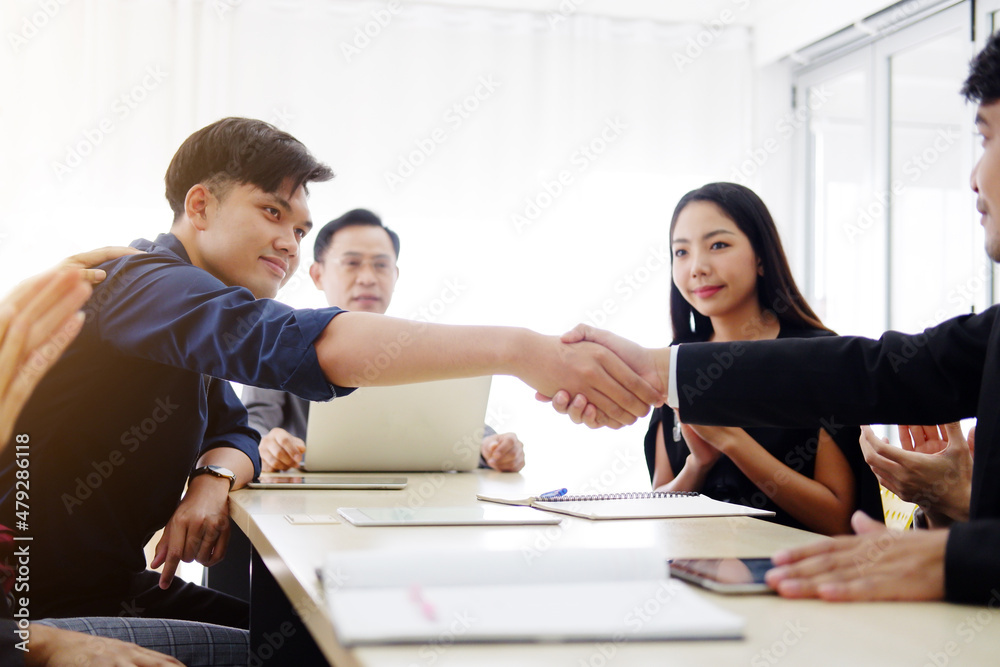 Smiling successful Asian businessmen and teamwork in black suit is shaking hand with partnership for a big project in meeting room at office. Business and marketing concept. Smiling successful Asian businessmen and teamwork in black suit is shaking hand with partnership for a big project in meeting room at office. Business and marketing concept.