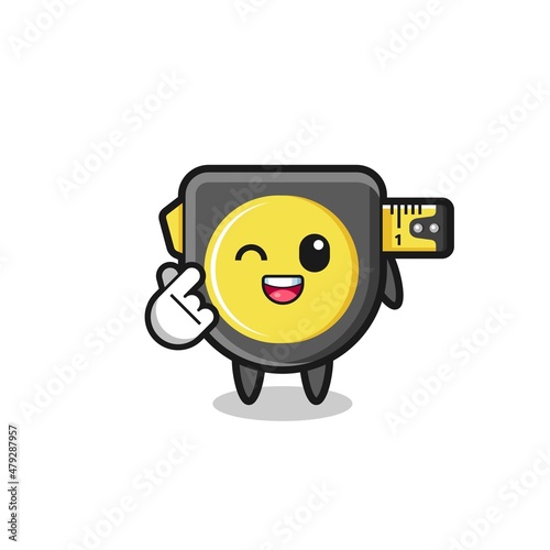 tape measure character doing Korean finger heart