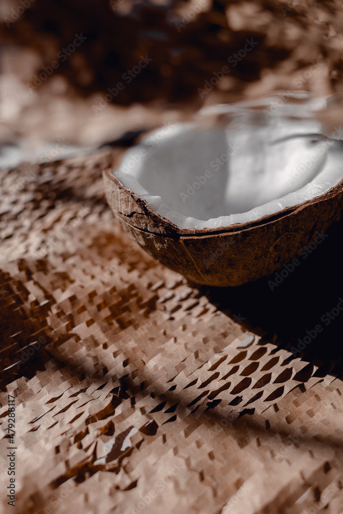 Half coconut on the table on packaging paper. Blurred background. Selective focus. Front view. Half coconut on the table on packaging paper. Blurred background. Selective focus. Front view.