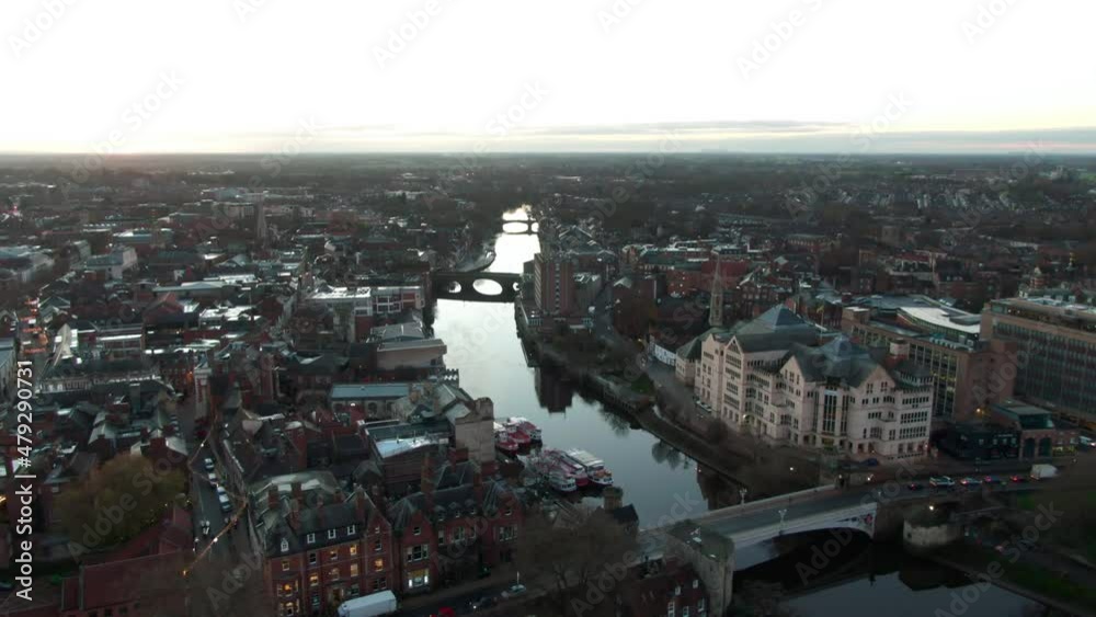 Drone view of river ouse flowing through the city of York, England at sunrise with bridges crossing the water at