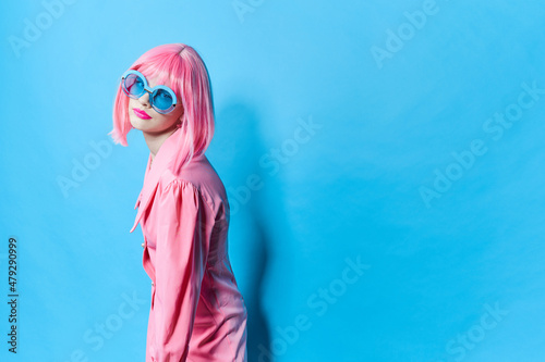 glamorous woman in blue glasses wears a pink wig isolated background