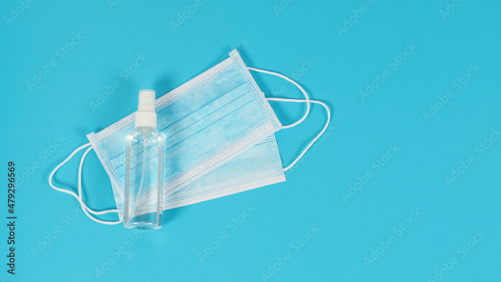 Two face masks and alcohol spray on blue background. Two face masks and alcohol spray on blue background.