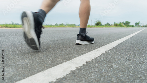 The legs of male athletes in black shoes are preparing to run on the paved road Outdoor exercise for weight loss and good health.Fitness and healthy lifestyle Competition and successful concept. © MemoryMan