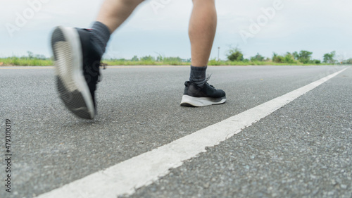 The legs of male athletes in black shoes are preparing to run on the paved road Outdoor exercise for weight loss and good health.Fitness and healthy lifestyle Competition and successful concept.