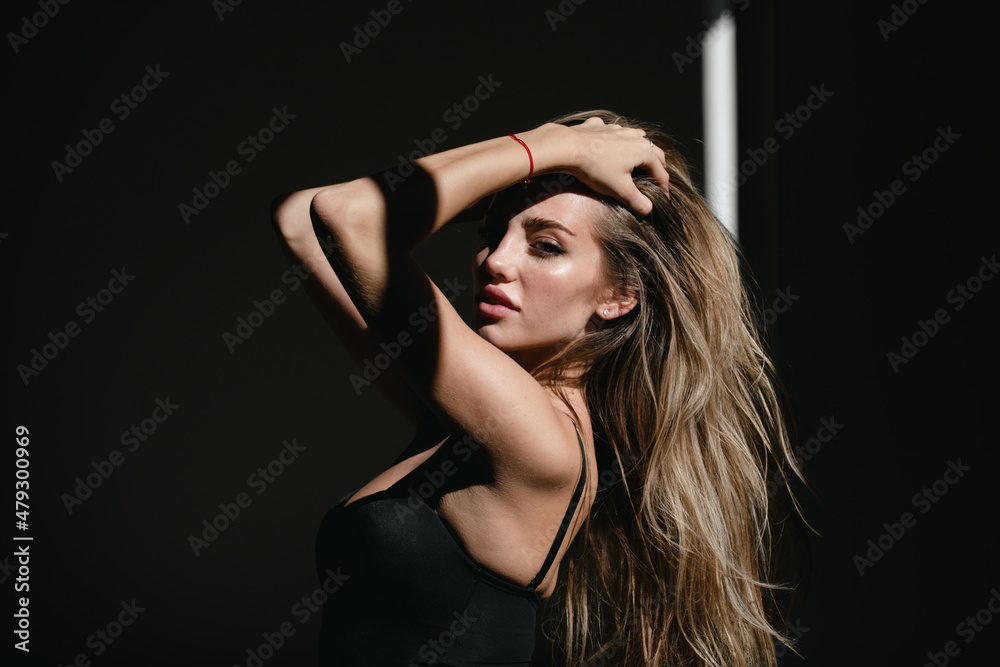 Fototapeta premium Fashion model, black vogue of elegant girl. High fashion look. Portrait of elegant woman with light on a black background. Beautiful female face in the darkness.