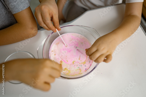 Children, girl, boy are having fun at home, experimenting with milk and paints