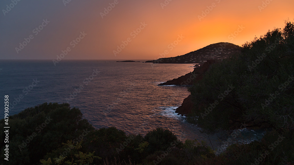 Stunning view of the mediterranean coast east of Saint-Raphael at the French Riviera after sunset with orange colored sky, rough sea.