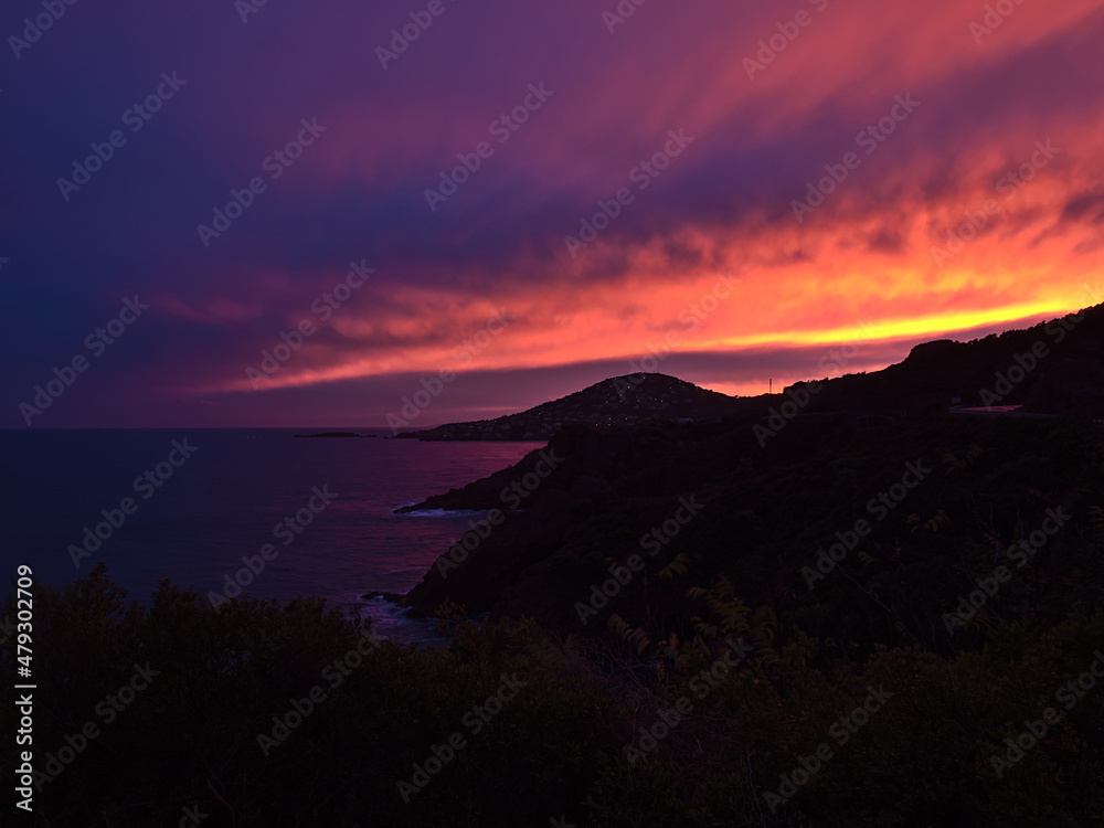 Beautiful sunset at the mediterranean coast near Saint-Raphael, French Riviera with dramatic colorful sky and the silhouettes of plants.