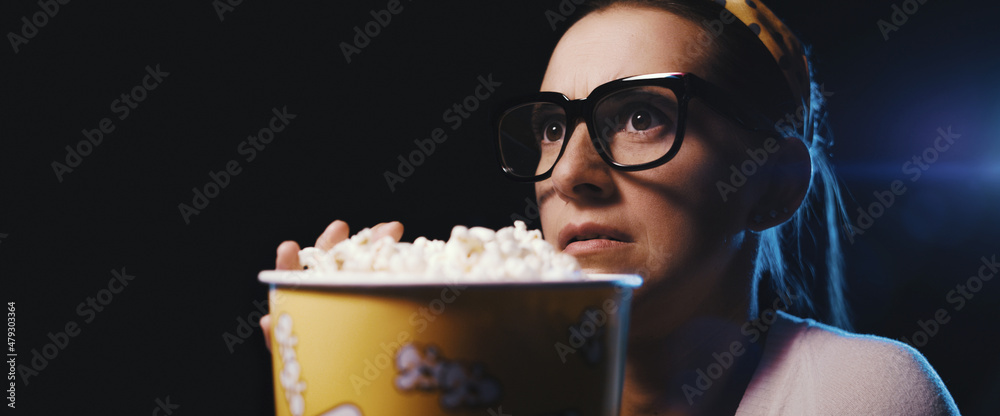 Woman watching a scary movie at the cinema