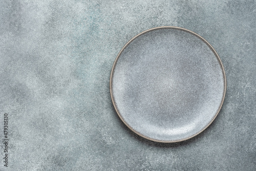 Empty gray plate on gray rustic concrete background. Top view, flat lay.