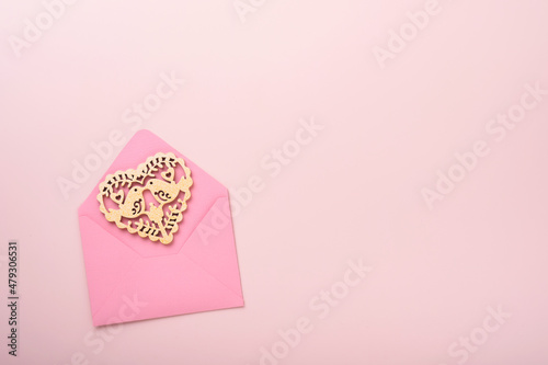Pink envelope with white openwork heart and red ribbon on pink background. Top view with copy space. Valentines day or Wedding romantic concept. Festive composition. Mock up. © kasia2003
