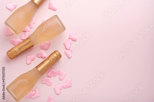 Valentines day greeting card with three champagne bottles and on pink background. Top view with space for greetings. Greeting card with copy space.