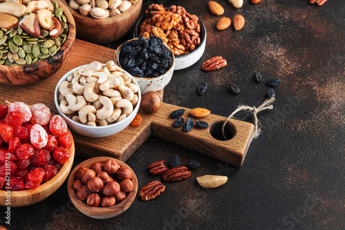 Dried fruits nuts in bowls set. Dry apricots, figs, raisins, walnuts, almonds and other. Healthy nutritious snacks. Brown table background, copy space