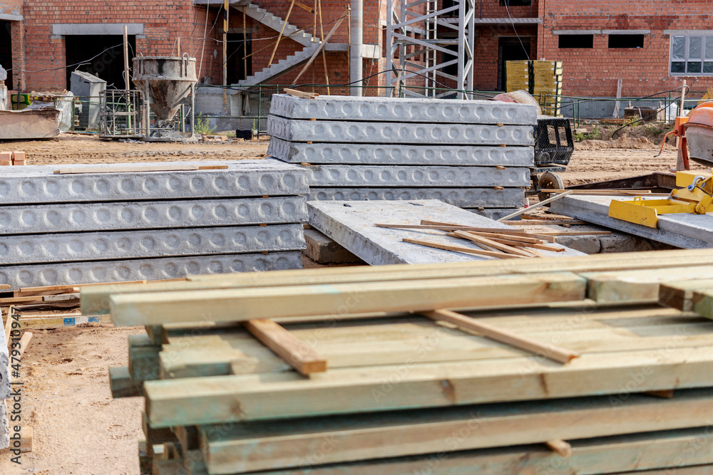 Reinforced concrete slabs and building materials at the construction site. Storage of materials for building a house. Industrial engineering. Reinforced concrete slabs and building materials at the construction site. Storage of materials for building a house. Industrial engineering.