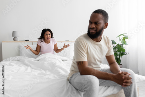 Sad young black man listen wife, woman freaking out and yells at unhappy husband, swear in bedroom interior
