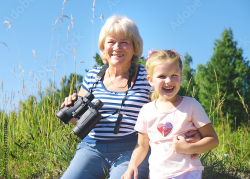 Little girl with her grandmother looking through binoculars outdoor photo